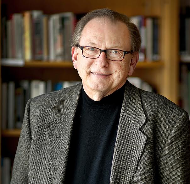 Man with glasses in a blazer and shirt.