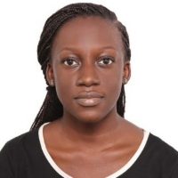 Young woman with braided hair, neutral expression, wearing a black shirt with white accents, plain white background.