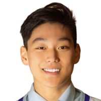 Young man with short dark hair smiling directly at the camera, wearing a collared shirt and a vest. Background is plain white.