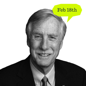Smiling man in a suit with a prominent mustache and light hair, a speech bubble above him reads February 18th.