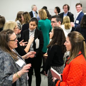 Group of professionals conversing at a networking event, with diverse participants engaging in discussions and sharing ideas.